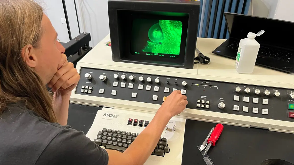 A volunteer operating an instrument console with a green-screen monitor