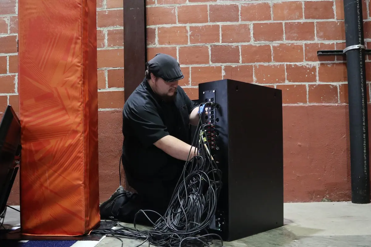 James kneeling beside an equipment rack, sorting a bundle of network cables