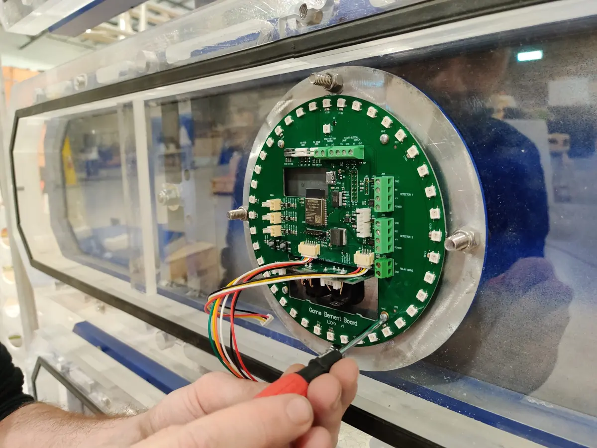A round green circuit board ringed with LEDs, held against a clear target housing