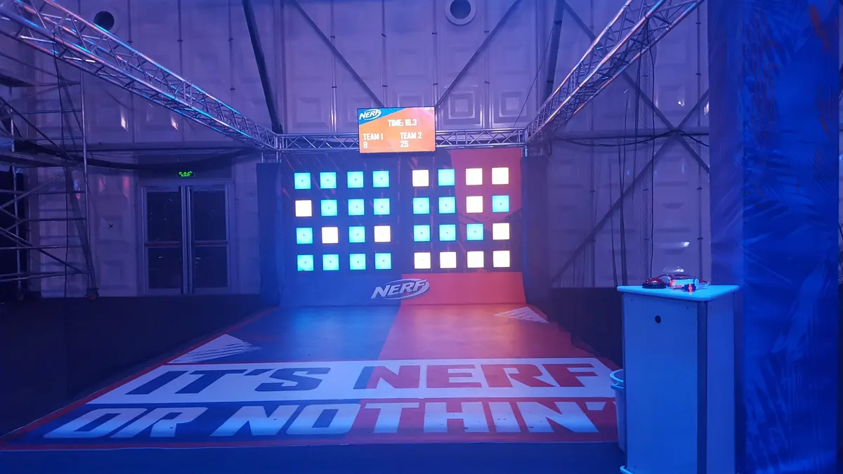 Two grids of square light-up target panels above an “It’s NERF or Nothin’” floor graphic