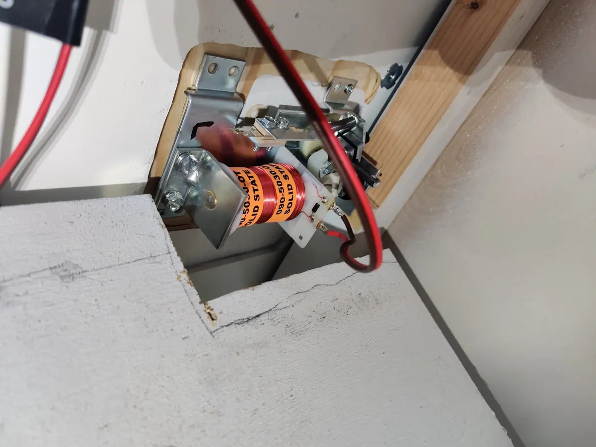A flipper solenoid installed in a notched opening beneath the playfield