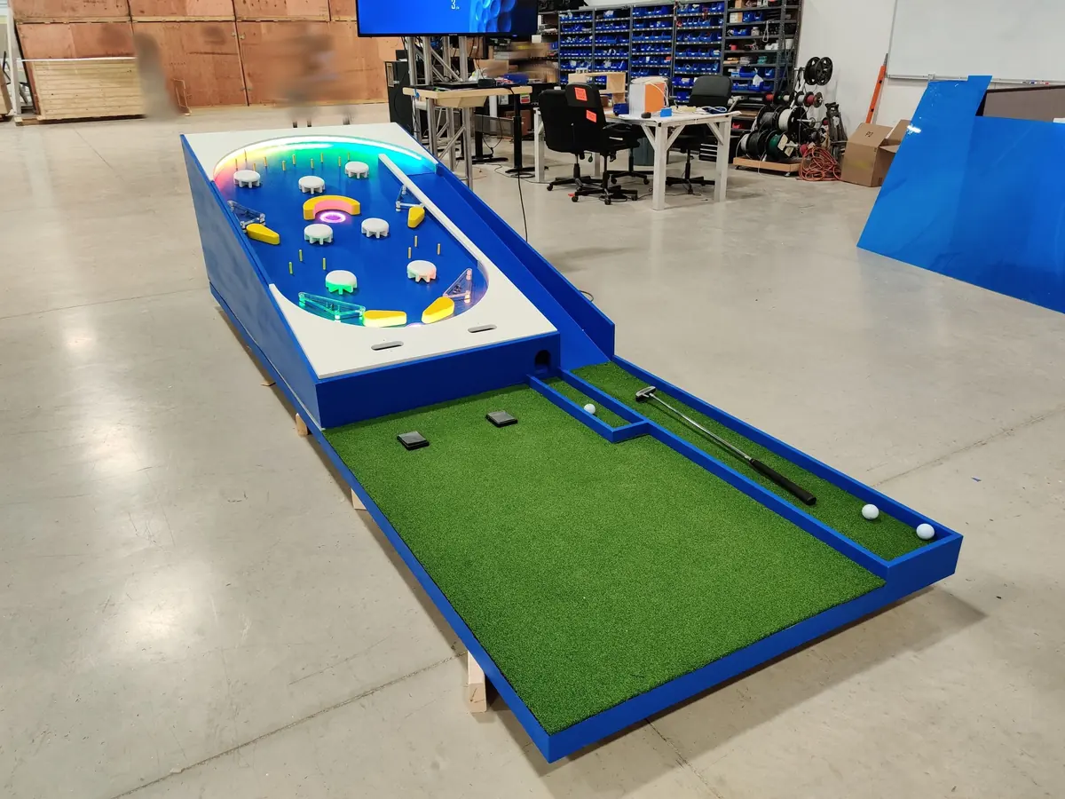 The finished Pinball Golf prototype on the shop floor: a blue pinball playfield leading into a putting green