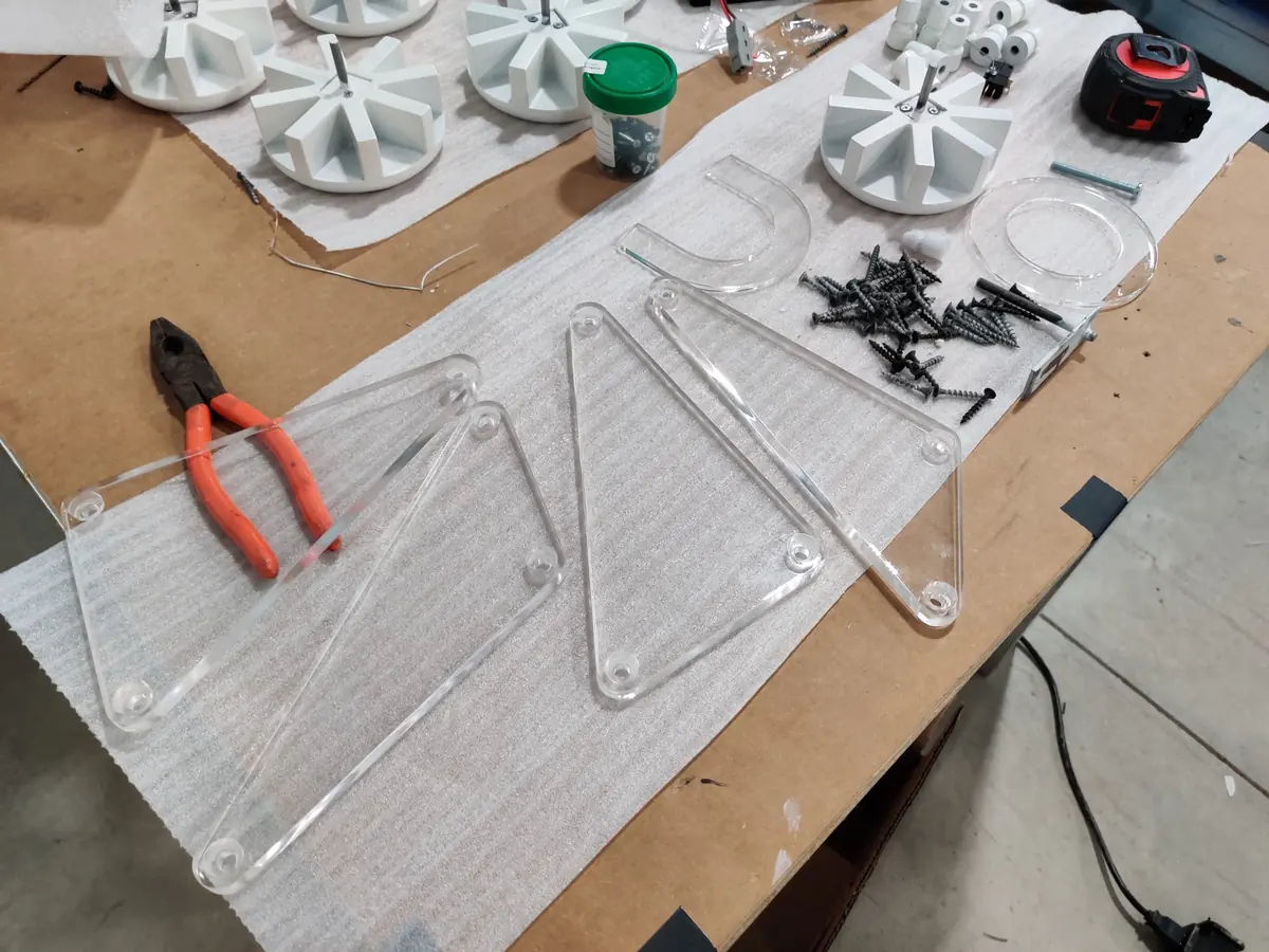 Clear acrylic slingshot test pieces and cast spinners laid out on a workbench
