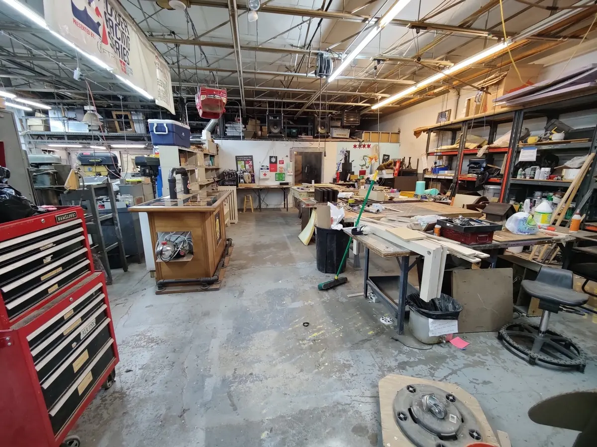 PS1’s general work area: long benches, tool chests, and shelving under fluorescent lights