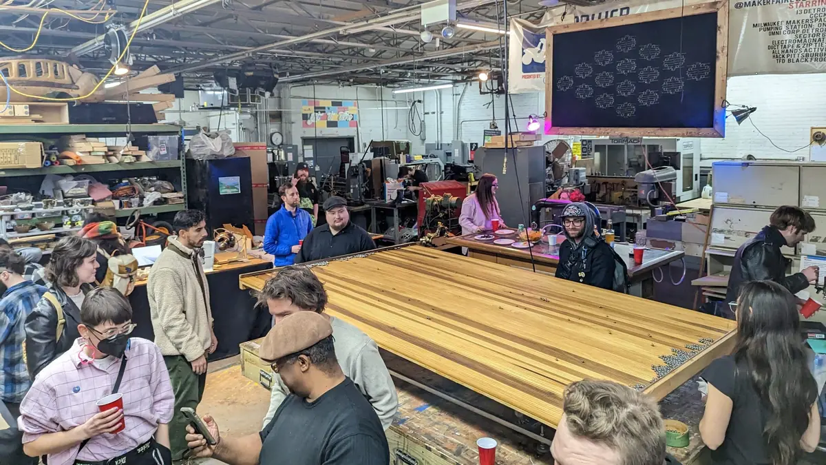 A crowd of members and guests gathered around a large table at a PS1 art show