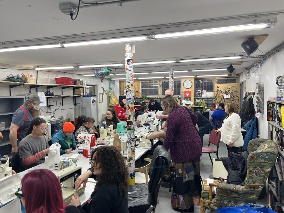 Members seated around tables with sewing machines during a class in the lounge